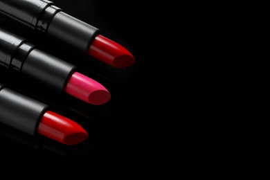 Photo of Many bright lipsticks on black background, space for text