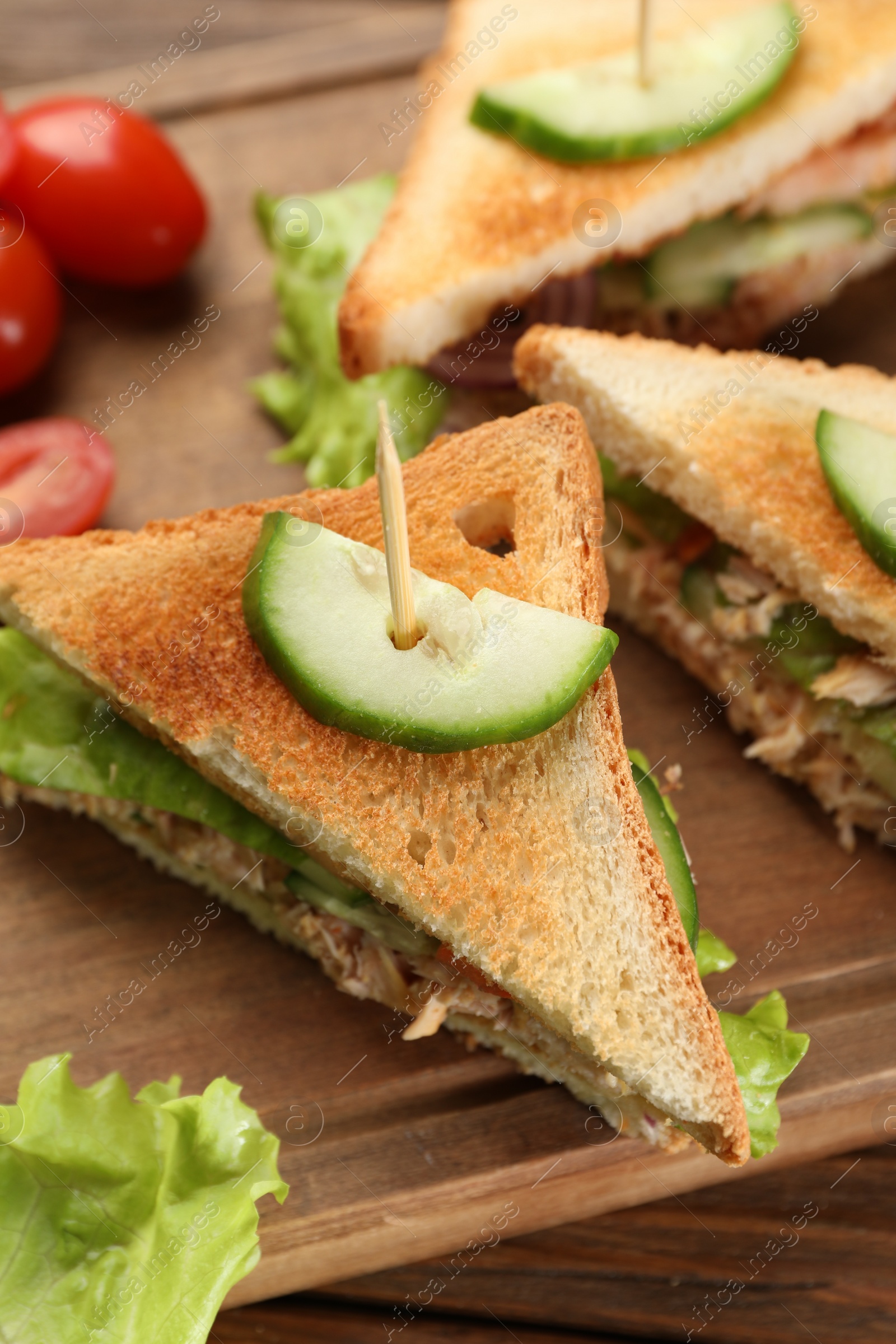 Photo of Delicious sandwiches with tuna and vegetables on wooden board, closeup