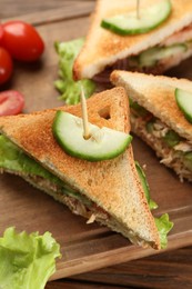 Delicious sandwiches with tuna and vegetables on wooden board, closeup