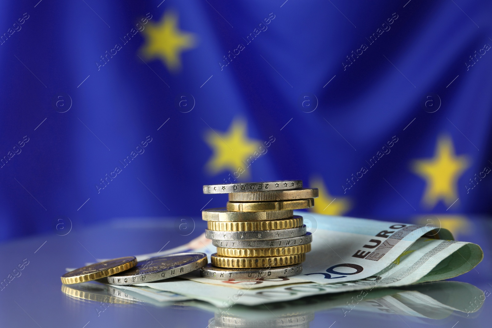 Photo of Coins and banknotes on table against European Union flag, space for text