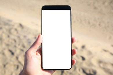 Photo of Man using weather forecast app on smartphone near sand outdoors, closeup