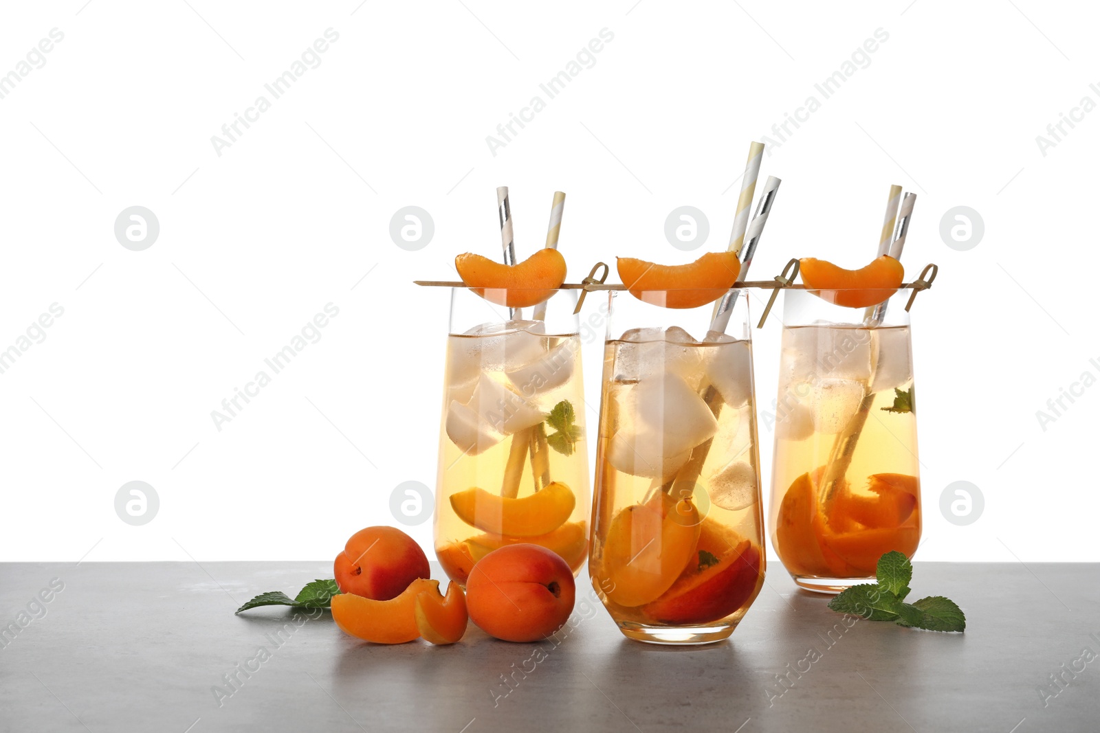 Photo of Delicious refreshing drink with apricot on grey table against white background