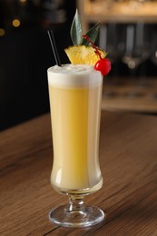 Photo of Tasty Pina Colada cocktail on wooden bar countertop