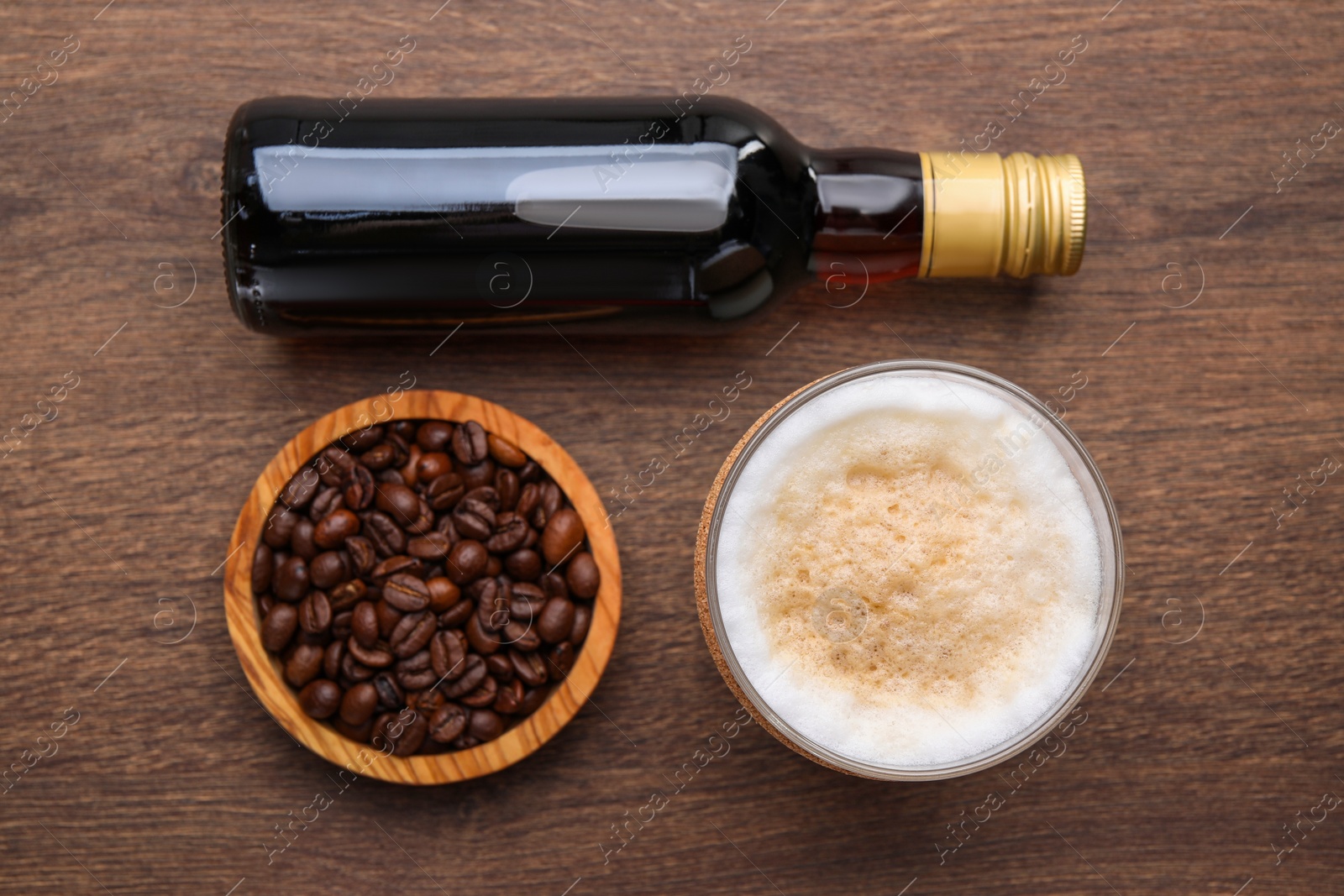 Photo of Bottle of delicious syrup, glass of coffee and beans on wooden table, flat lay