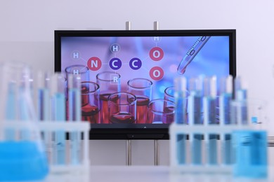 Photo of Modern interactive board and laboratory glassware in classroom