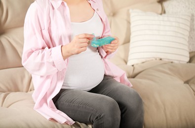 Photo of Pregnant woman holding box with pills at home, closeup