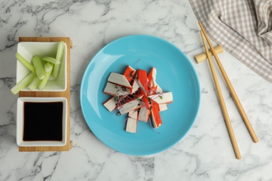 Fresh crab sticks with soy sauce and celery served on white marble table, flat lay