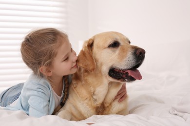 Photo of Young girl with her adorable dog on bed at home