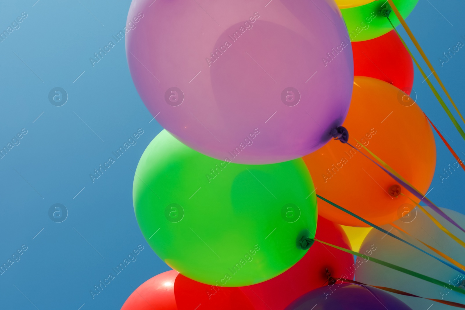 Photo of Bunch of colorful balloons against blue sky, low angle view