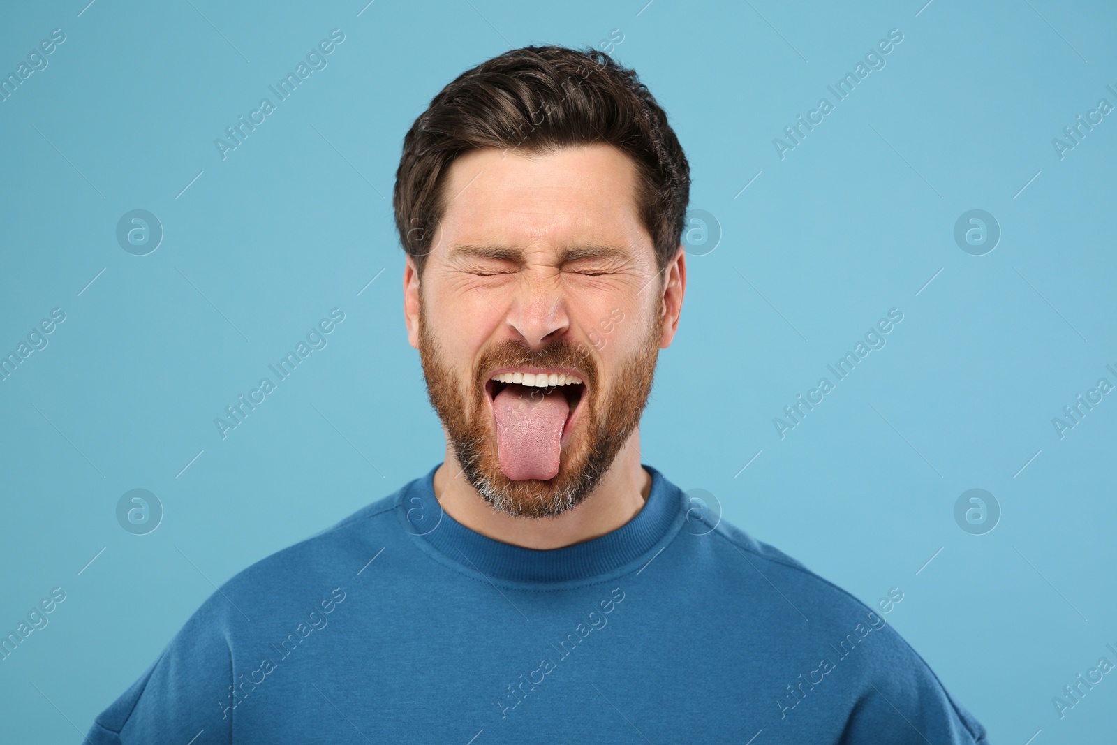 Photo of Man showing his tongue on light blue background