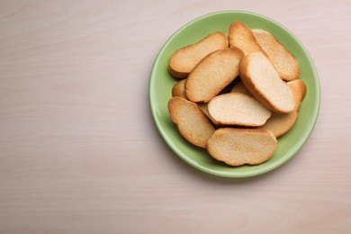 Photo of Plate of hard chuck crackers on wooden table, top view. Space for text