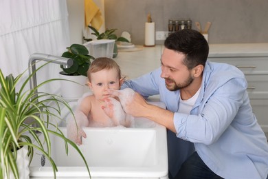 Photo of Father washing his little baby in sink at home