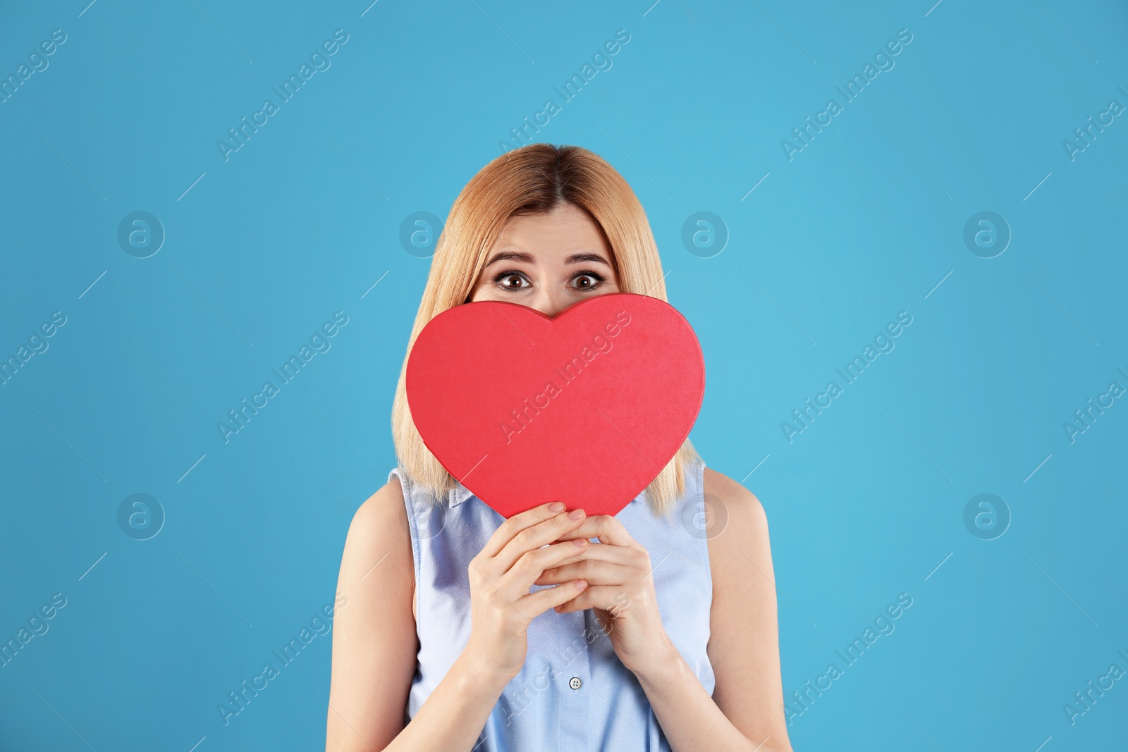Photo of Beautiful woman with heart shaped box on color background