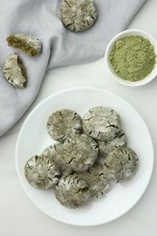 Photo of Plate with tasty matcha cookies and powder on white table, flat lay