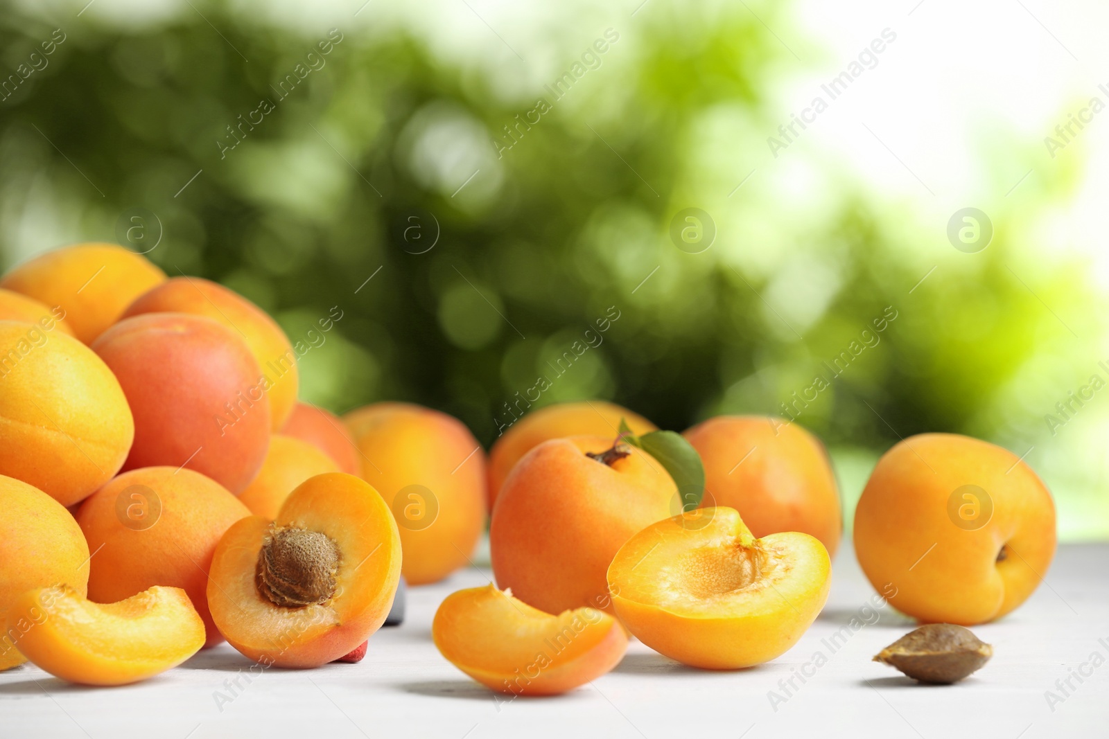 Photo of Delicious ripe sweet apricots on white table against blurred background, space for text