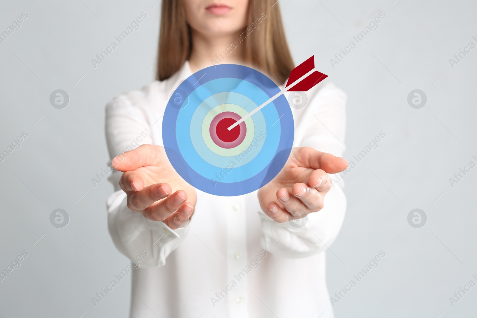 Image of Young woman and dartboard on light background, closeup