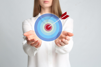 Image of Young woman and dartboard on light background, closeup