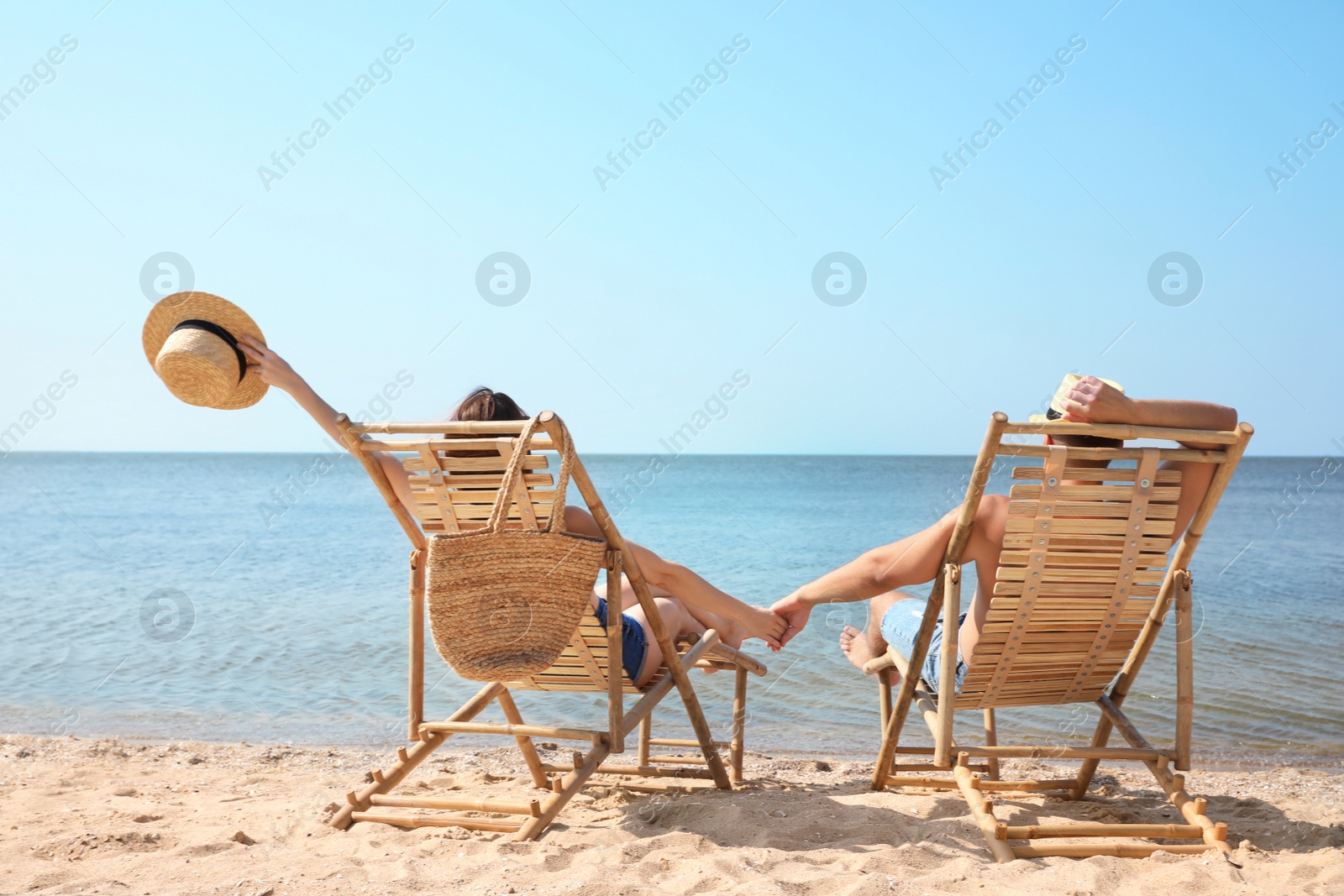 Photo of Young couple relaxing in deck chairs on beach