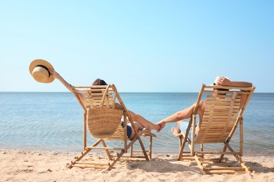 Photo of Young couple relaxing in deck chairs on beach