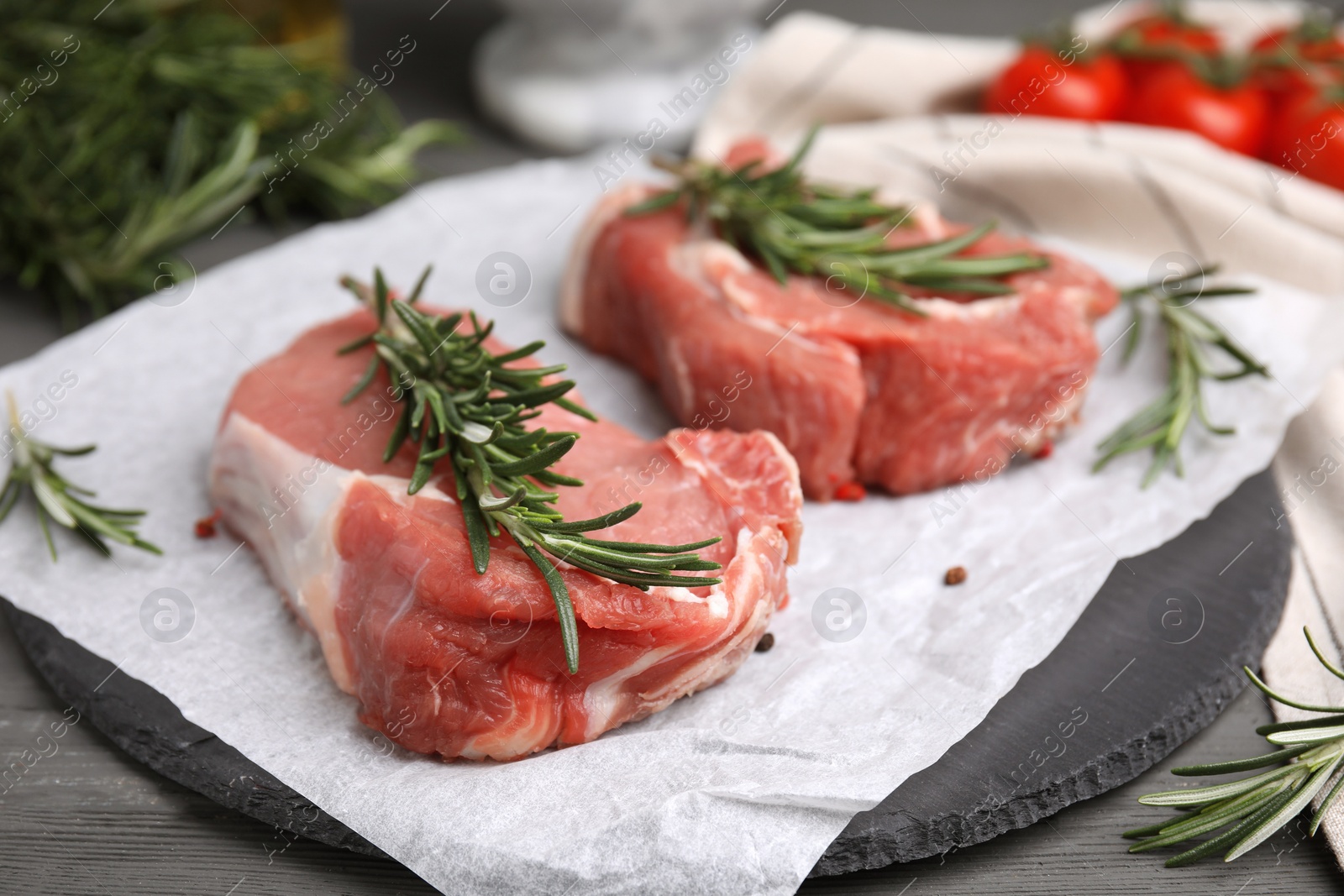 Photo of Fresh raw meat with rosemary on grey wooden table, closeup