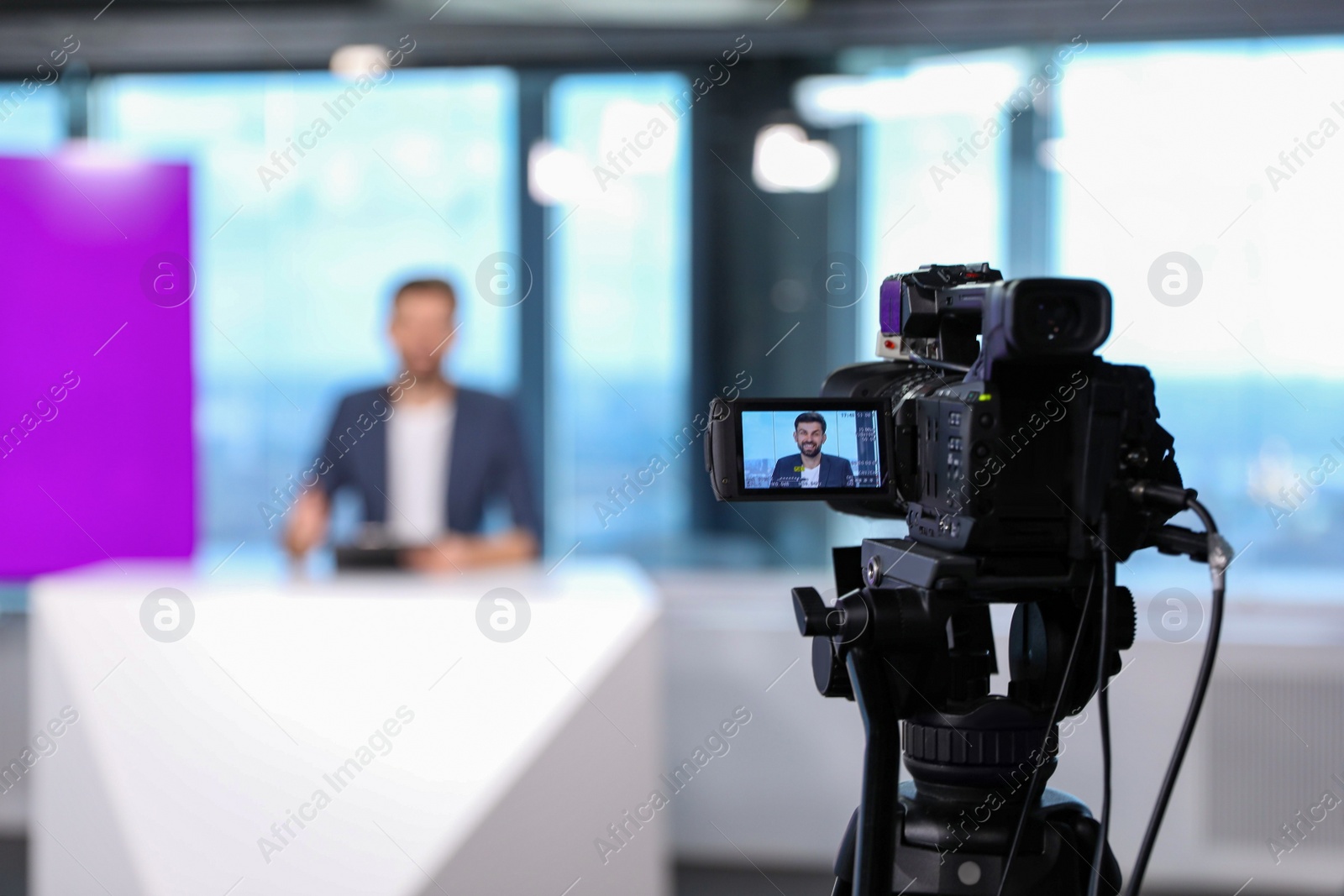 Photo of Presenter working in studio, focus on video camera