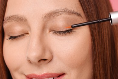 Photo of Woman applying serum onto eyelashes, closeup view