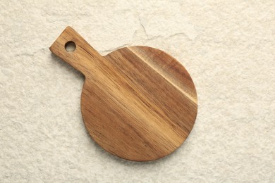 Photo of Wooden cutting board on beige table, top view. Space for text