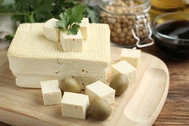 Photo of Cut tofu with olives and soya beans on wooden table, closeup