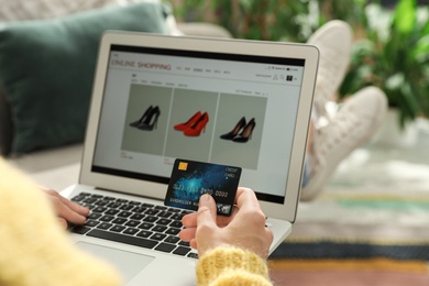 Photo of Woman with credit card using laptop for online shopping at home, closeup