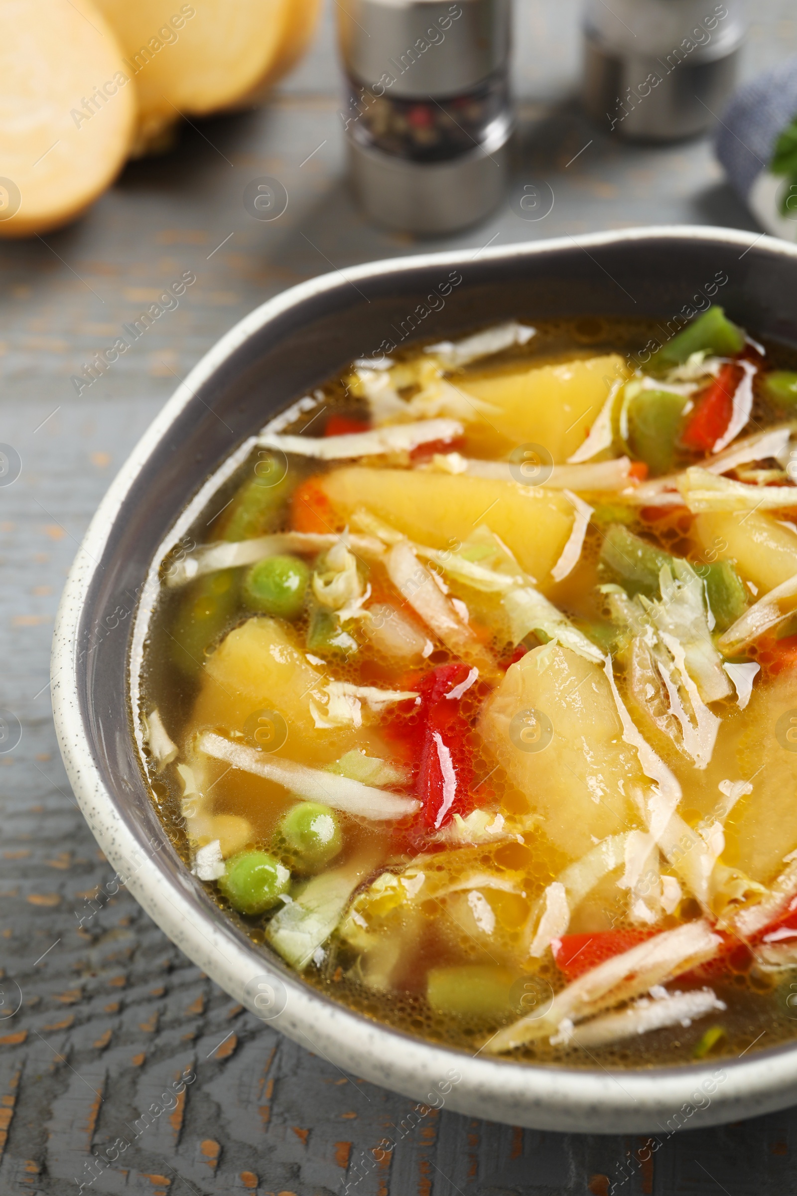 Photo of Bowl of delicious turnip soup on grey wooden table, closeup