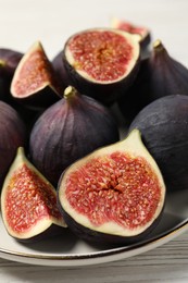 Whole and cut ripe figs on white wooden table, closeup