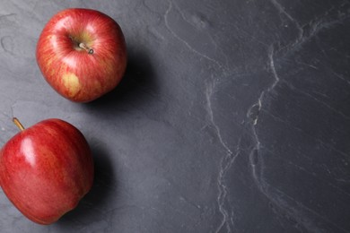 Photo of Ripe red apples on black textured table, flat lay. Space for text