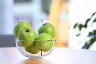 Bowl of fresh green apples on table indoors. Space for text