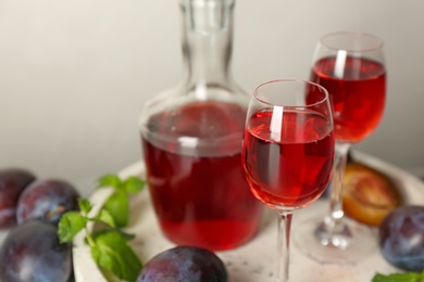 Photo of Delicious plum liquor served on tray, closeup. Homemade strong alcoholic beverage
