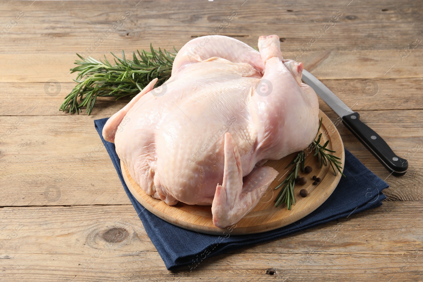 Photo of Fresh raw chicken with spices and knife on wooden table