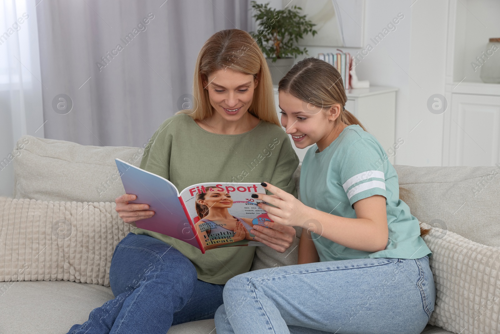 Photo of Happy mother and her teenage daughter spending time together with magazine at home