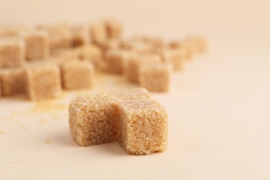 Photo of Brown sugar cubes on beige background, closeup. Space for text