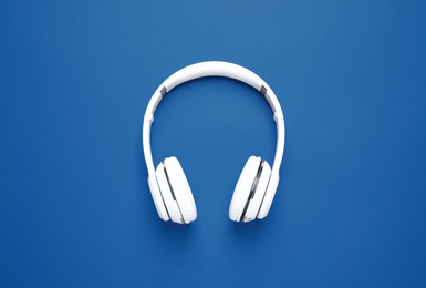 Photo of Headphones on bright background, top view. Color of the year 2020 (Classic blue)