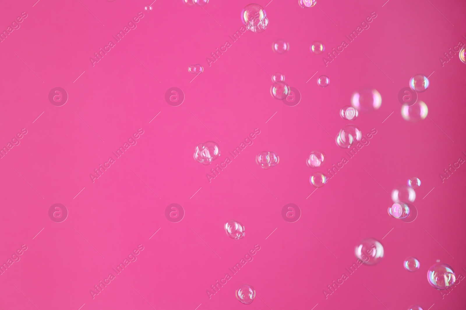 Photo of Beautiful transparent soap bubbles on pink background, space for text
