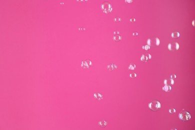 Photo of Beautiful transparent soap bubbles on pink background, space for text