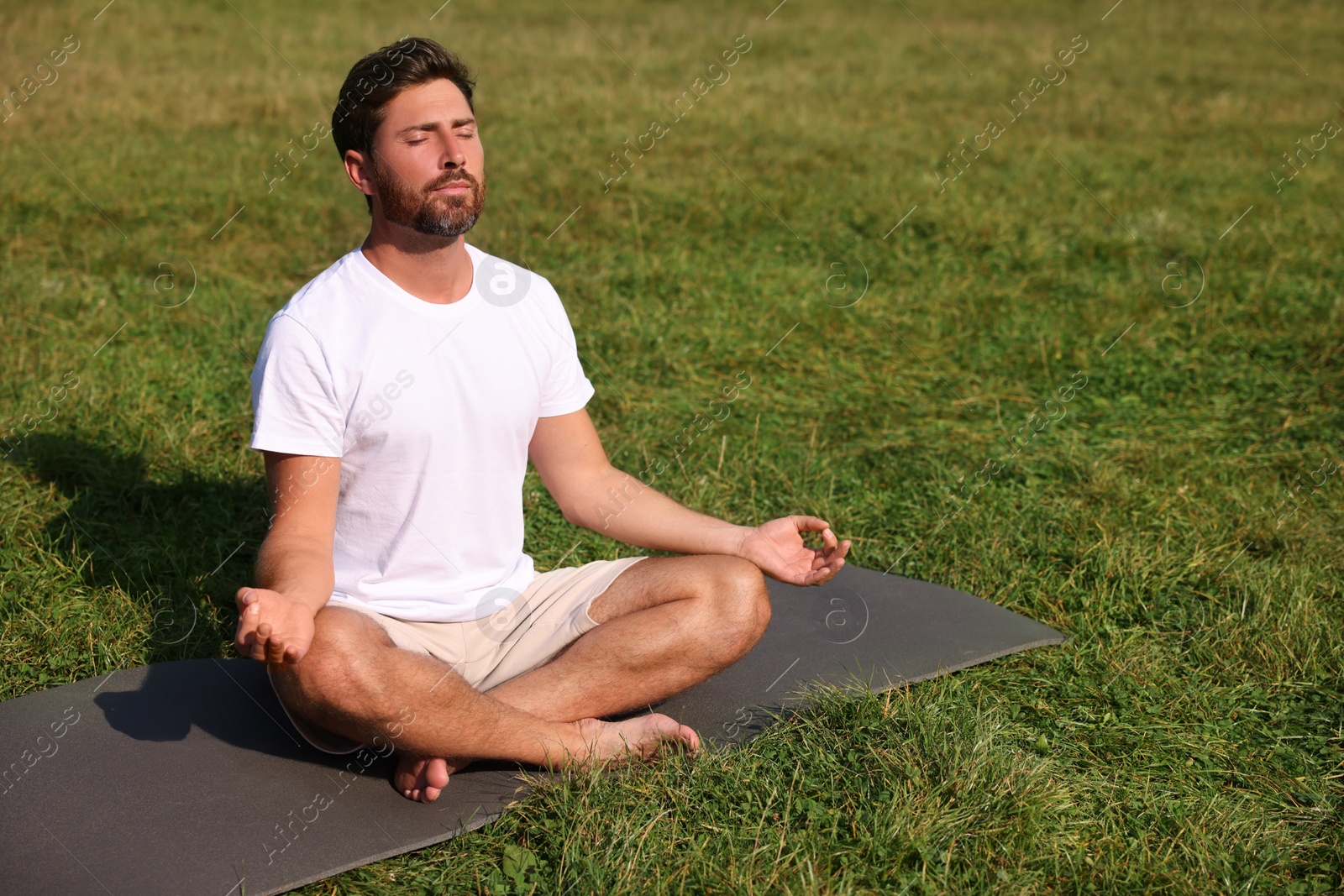 Photo of Man practicing yoga on mat outdoors, space for text. Lotus pose