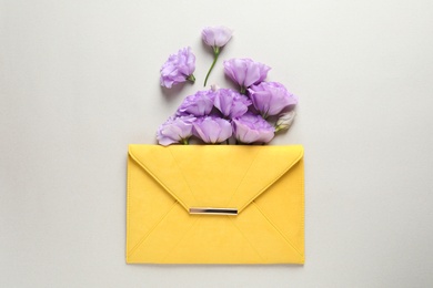 Photo of Beautiful Eustoma flowers and envelope on gray background