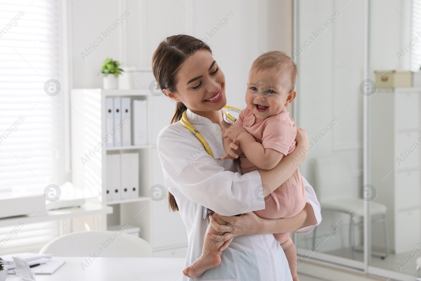 Photo of Young pediatrician with cute little baby in clinic