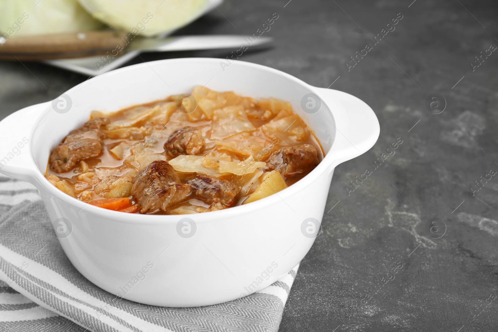 Photo of Tasty cabbage soup with meat and carrot on grey table, closeup. Space for text