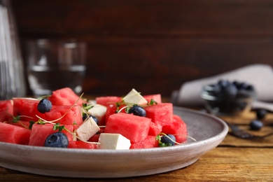 Photo of Delicious salad with watermelon, blueberries and feta cheese on wooden table, closeup. Space for text