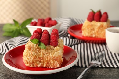 Piece of delicious Napoleon cake with fresh raspberries served on grey table, closeup. Space for text