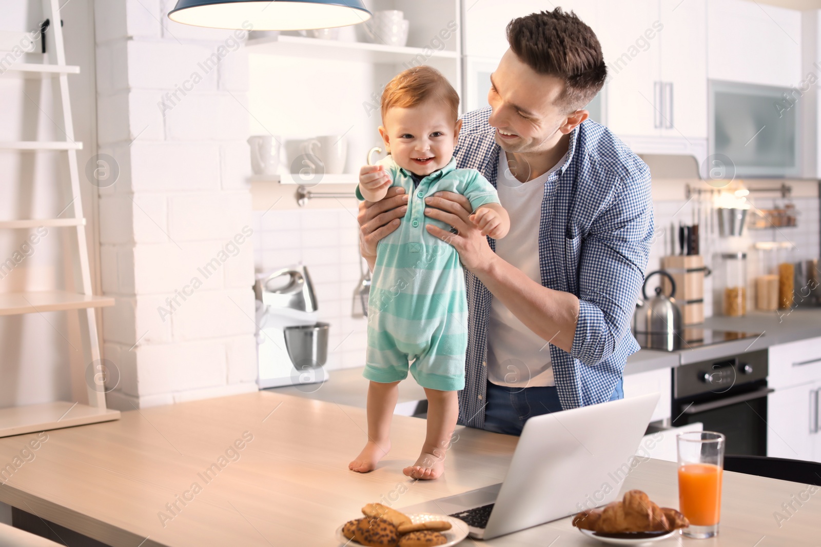 Photo of Young father with his cute little son in kitchen