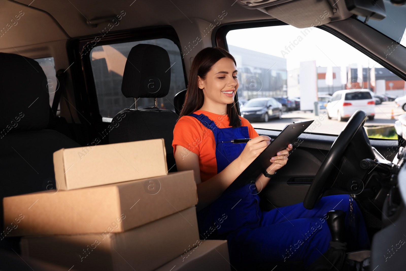 Photo of Courier with clipboard checking packages in car