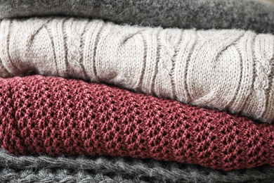 Photo of Stack of warm knitted clothes as background