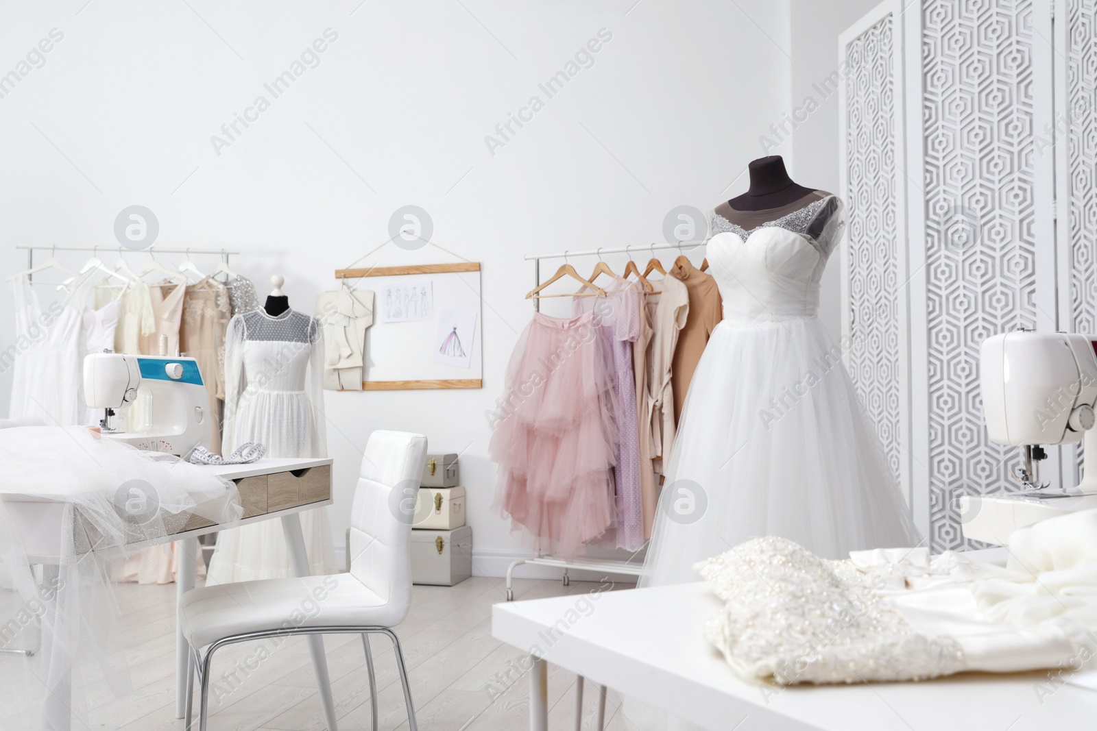 Photo of Dressmaking workshop interior with wedding dresses, female clothes and equipment